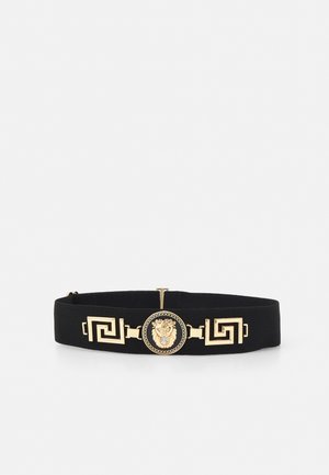 Ceinture élastique noire avec des accents géométriques dorés et un médaillon central présentant un motif de tête de lion.
