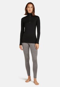 Black long-sleeve top with a half-zip collar paired with light gray leggings. Both garments have a smooth, fitted texture.