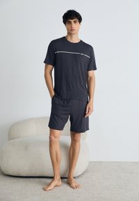 Set de îmbrăcăminte de interior de culoare gri �închis, format dintr-un tricou cu mânecă scurtă având o dunga albă decorativă și pantaloni scurți asortați, confecționat dintr-un material moale.