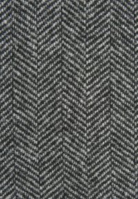 Stoff im Fischgrätmuster in Schwarz- und Grautönen, mit einer strukturierten Webart, die sichtbare Fasern aufweist, und einem gleichmäßigen Zickzackdesign.