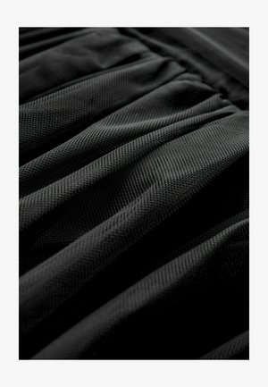 Tissu noir texturé avec un design plissé, montrant un motif uniforme et une apparence douce. Accent sur les couches et les plis du matériau.