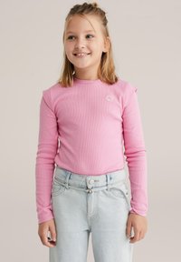 Bluza roz prăfuit cu mâneci lungi, cu guler rotund și broderie mică florală, asortată cu blugi bleu deschis cu talie înaltă.