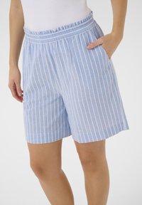 Pantaloni corti azzurri realizzati in un tessuto morbido, con strisce verticali bianche, una vita arricciata elastica e tasche laterali.