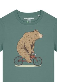 Groene t-shirt met een illustratie van een bruine beer die op een rode fiets rijdt. De beer heeft een glimlachende uitdrukking en gedetailleerde vachttextuur.