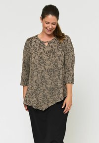 Leopárdmintás tunika felső barna és fekete színben, háromnegyedes ujjakkal és kulcslyuk nyakkivágással, fekete szoknyával párosítva.