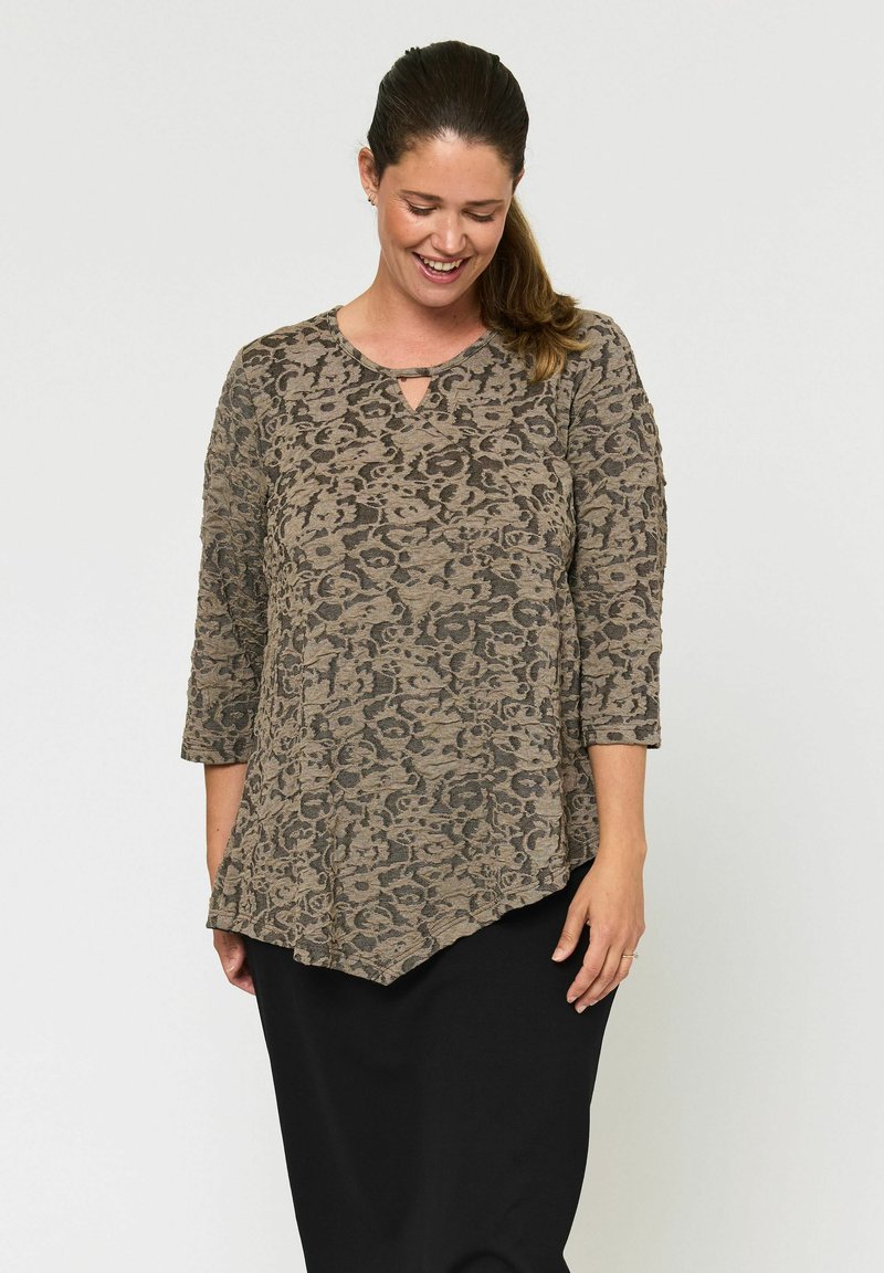 Leopárdmintás tunika felső barna és fekete színben, háromnegyedes ujjakkal és kulcslyuk nyakkivágással, fekete szoknyával párosítva.