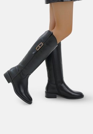 Bottes noires montant jusqu'au genou en cuir lisse, dotées d'un bout arrondi, d'un petit talon carré et d'une boucle décorative sur le côté extérieur.