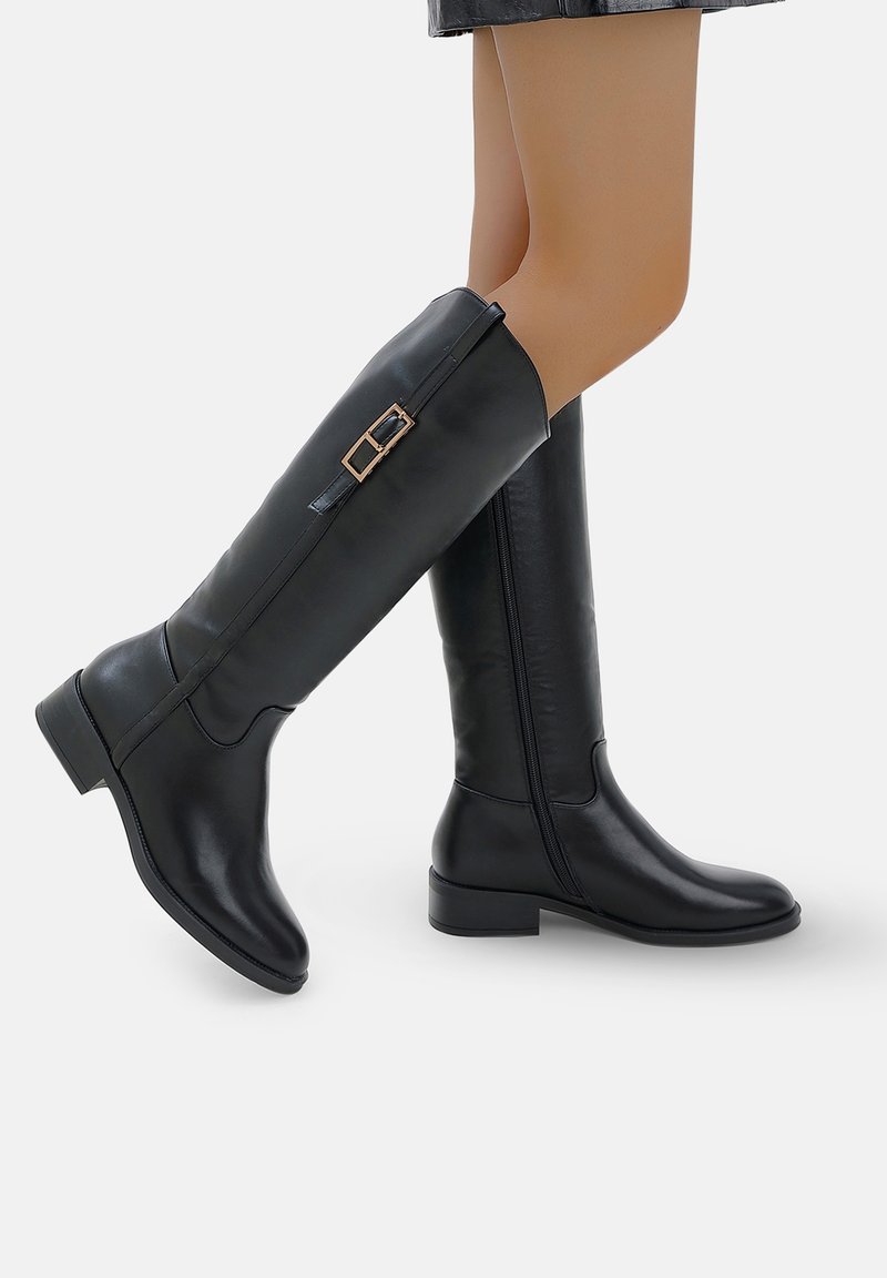 Botas negras hasta la rodilla hechas de cuero suave, con punta redondeada, tacón bajo tipo bloque y una hebilla decorativa en el lado exterior.