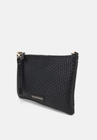 Svart vävd läderclutch med en slät yta, guldfärgad hårdvara och varumärkeslogotyp. Dragkedjestängning med ett kort avtagbart band.