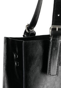 Borsa tote in pelle nera con una texture liscia, dotata di tracolla removibile, accessori in metallo e dettagli di cucitura lungo i bordi.