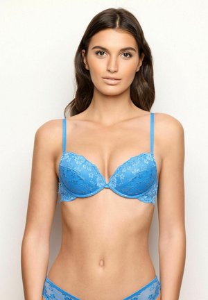 Blauwe kant beha met gevoerde cups, verstelbare bandjes en ingewikkelde bloemenpatronen. Bijpassende kanten slipjes zichtbaar. Gladde textuur.