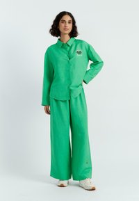 Groene linnen overhemd en wijde broek, met knoopsluiting en geborduurde details, textuur, casual pasvorm met een lichte uitstraling.