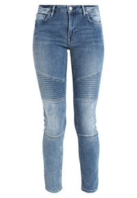 Jeans de corte skinny en denim azul claro, con detalles de paneles cosidos, desvanecidos y un diseño sutilmente desgastado en una pierna.