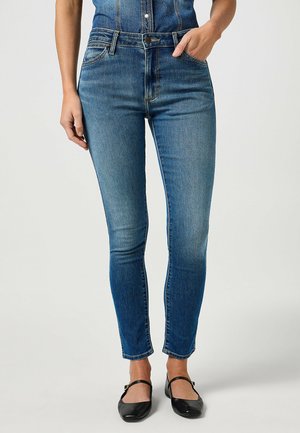 Slank jeans i mellemvaske denim med høj talje, subtilt slid, fem-lommemodel og en tætsiddende silhuet med ankellængde.