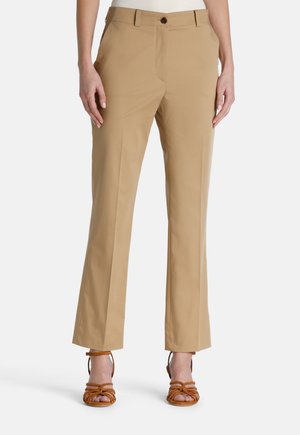 Beige hameet, jotka on muotoiltu suoraan lahkeeseen, varustettu nappikiinnityksellä ja taskuilla. Tasainen kangas, jossa on mattapinta.