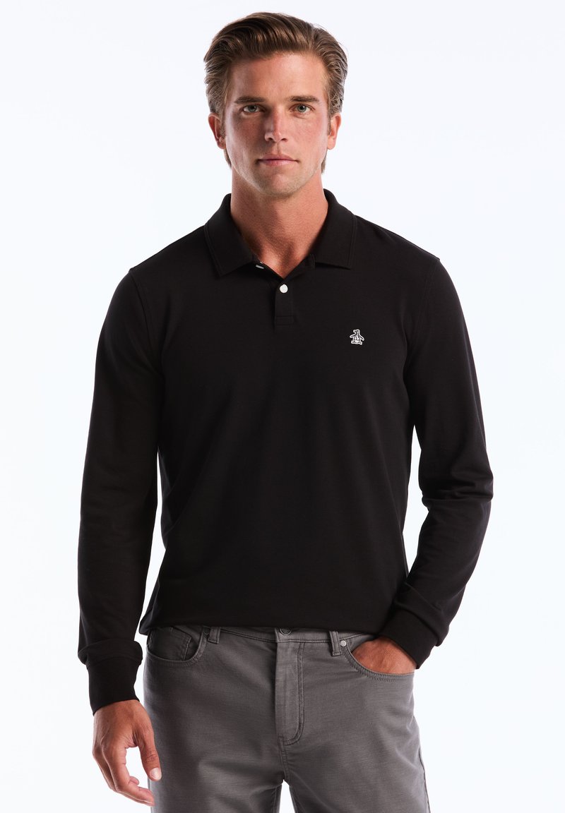 Zwarte langemouwen poloshirt met een kraag en een klein pinguïnlogo op de borst, gecombineerd met grijze jeans. Glad textuur en getailleerd ontwerp.