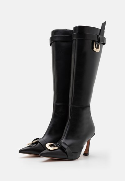 Botas de cuero negras hasta la rodilla con punteras puntiagudas, detalles de hebilla dorada y tacón de aguja. Textura suave y diseño estructurado.