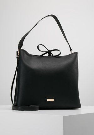 Schwarze Lederhandtasche mit obenliegendem Griff, abnehmbarem Schulterriemen und dekorativer Schleife auf weißem Hintergrund.