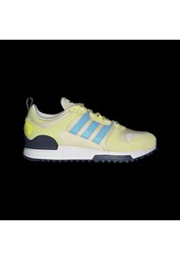 Zapatilla deportiva de color amarillo claro con rayas azules, materiales de malla y ante, suela de goma y una pestaña en la parte trasera. Presenta un collar acolchado.