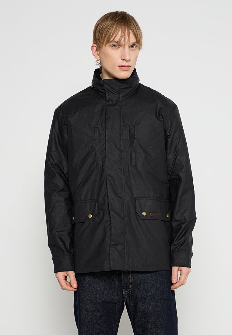 Veste noire avec un col haut, fermeture éclair à l'avant et poches boutonnées. Elle se distingue par un tissu texturé et une coupe décontractée.