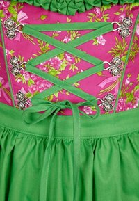 Tradiční oděv s růžovým květinovým živůtkem, zeleným šněrováním a stříbrnými růžovými doplňky, v kombinaci s texturovanou zelenou sukní.