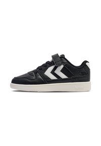 Schwarzer Sportschuh mit weißem Chevron-Muster, ausgestattet mit einem Riemen und Schnürsenkeln. Die Sohle ist cremfarben und mit "hummel" versehen.