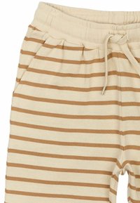 Beige och bruna randiga joggers gjorda av mjukt tyg, med elastisk midja och dragsko, sidofickor och en avslappnad passform.