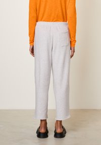 Grijze, loszittende joggingbroek met een gestructureerde stof, voorzien van een achterzak en een elastische tailleband, gestyled met een oranje top met lange mouwen.