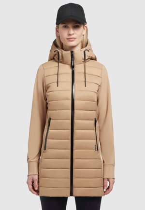 Veste matelassée beige avec capuche, fermeture éclair noire et deux poches latérales. Coupe slim avec poignets côtelés et texture de tissu lisse.