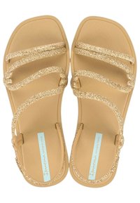 Sandali in oro glitter con suola piatta, dotati di tre cinturini ondulati e design a punta quadrata. La soletta presenta il logo blu di Ipanema.