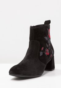 Czarne zamszowe botki za kostkę na słupku, z czerwonym i szarym haftem kwiatowym po bokach. Gładka tekstura i ostro zakończony design.
