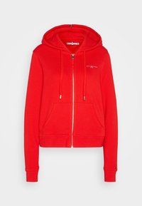 Červená mikina na zip vyrobená z měkké bavlněné směsi. Má přední kapsu a kapuci se stahovací šňůrkou. Zdůrazněno logem na hrudi.