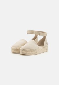 Beige kankaan espadrilles dengan platform dililit jute, tali pergelangan kaki yang dapat disesuaikan, dan desain jari kaki bulat tertutup. Konstruksi yang sederhana dan ringan.