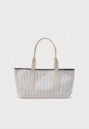 Bolsa tote blanca con franjas negras verticales, asas beige y un pequeño cierre central con botón dorado sobre un fondo liso.