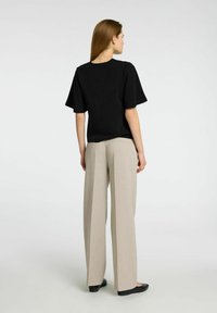 Svart kortärmad topp som matchas med ljusbeiga vida byxor. Outfiten har en enkel design med slät textur och rena linjer.
