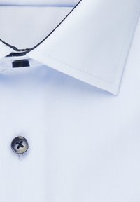 Jasnoniebieska koszula z wyraźnym kołnierzykiem, pojedynczym czarnym guzikiem i delikatnie teksturowanym materiałem. Posiada ciemne przeszycia wzdłuż krawędzi kołnierzyka.