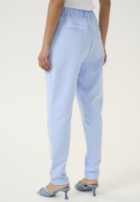 Joggers leggeri azzurri, con vita elastica, due tasche posteriori e un taglio affusolato. Texture liscia, design casual.