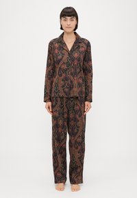 Conjunto de pijama estampado em tecido escuro, com intricado padrão paisley em vermelho, verde e dourado. Camisa de manga longa com colarinho e calças largas.