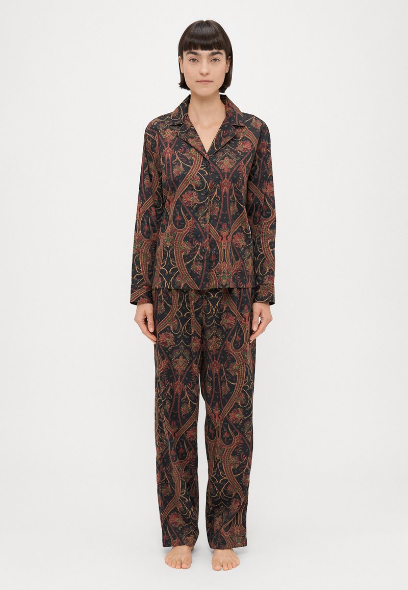 Conjunto de pijama estampado em tecido escuro, com intricado padrão paisley em vermelho, verde e dourado. Camisa de manga longa com colarinho e calças largas.