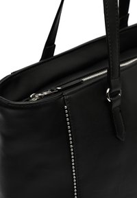 Black leather tote bag featuring silver-tone studs along the side seam, top zipper closure, and two sturdy handles.
