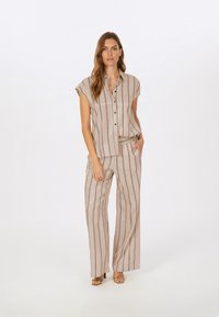 Beige, kurzärmeliges Hemd mit Knöpfen und vertikalen Streifen, kombiniert mit passenden, locker sitzenden Hosen mit elastischem Bund und seitlichen Taschen.