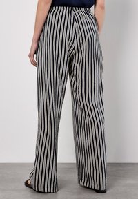Pantaloni a gamba larga a righe blu navy e crema con vita elastica e tessuto testurizzato, caratterizzati da righe verticali che percorrono la lunghezza delle gambe.