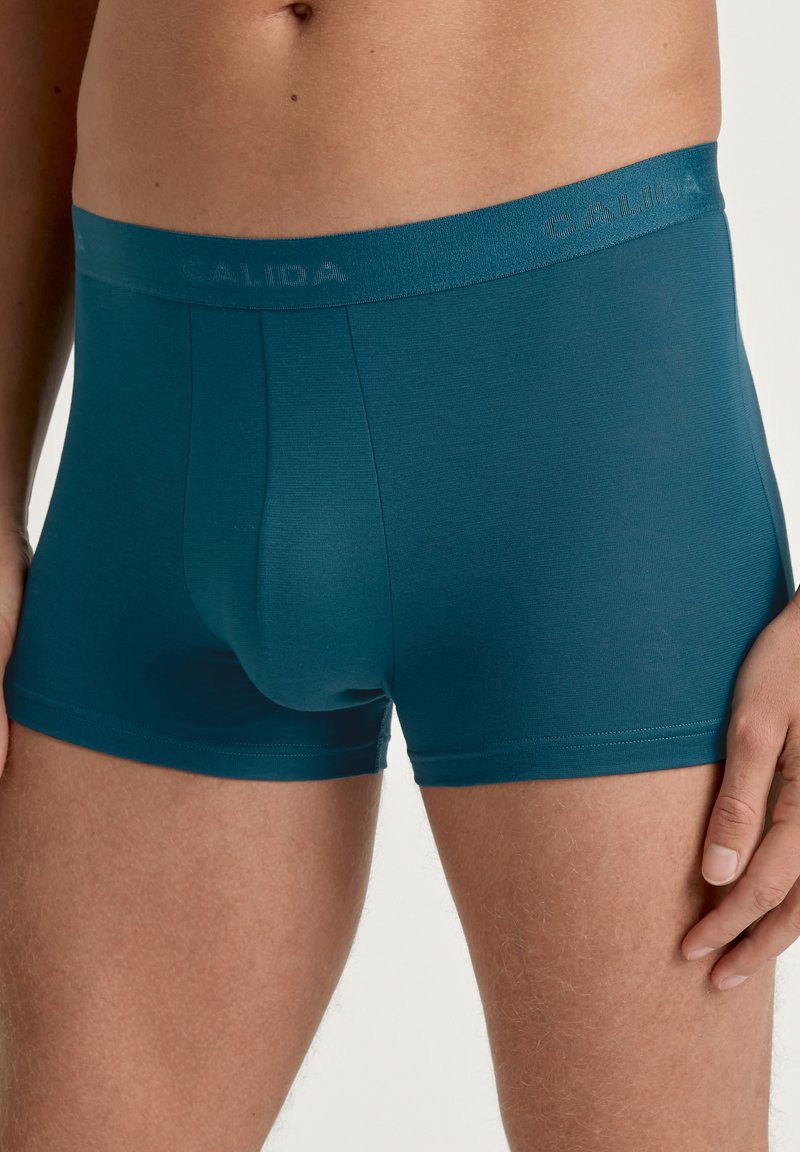 Teal bokser shorts van zacht materiaal, met een logo op de elastische tailleband en een snug fit met minimale naden voor comfort en ondersteuning.