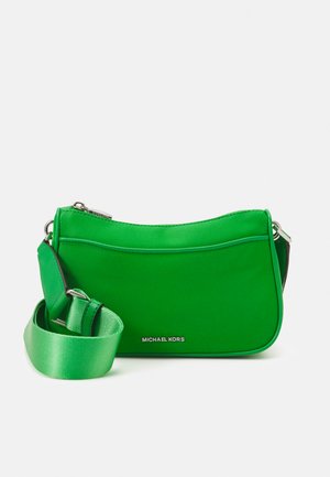 Bolso sintético verde con una textura suave, forma curva y una correa verde desmontable. Presenta herrajes plateados y detalle del logo.