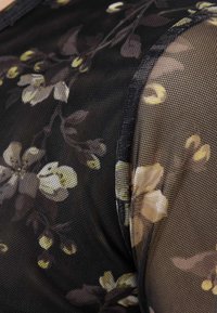 Μαύρο δίκτυ ύφασμα με λουλουδένια σχέδια σε ήπιους μπεζ και πράσινους τόνους, με διαφανή υφή και ομαλά τελειώματα.