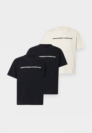 Tři trička Emporio Armani s krátkým rukávem a kulatým výstřihem, dvě černá a jedno bílé, každé s logem značky přes hruď.