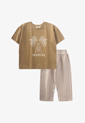 Tan short-sleeve T-shirt with palm tree graphic and "TROPICAL" text, paired with light beige striped pants with an elastic waistband.