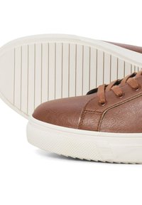 Brown leather sneaker with a textured upper, round toe, and white rubber sole featuring a patterned tread and contrasting laces.