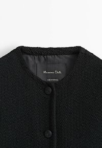 Musta tekstuuri kardigan, jossa on pyöreä kaula-aukko, kaksi mustaa nappia ja kangasetiketti, joka osoittaa "Massimo Dutti, Valmistettu Portugalissa."