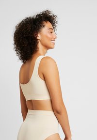 Beige sömlös bralette med breda remmar och en bekväm passform, med en mjuk textur och minimalistisk design.